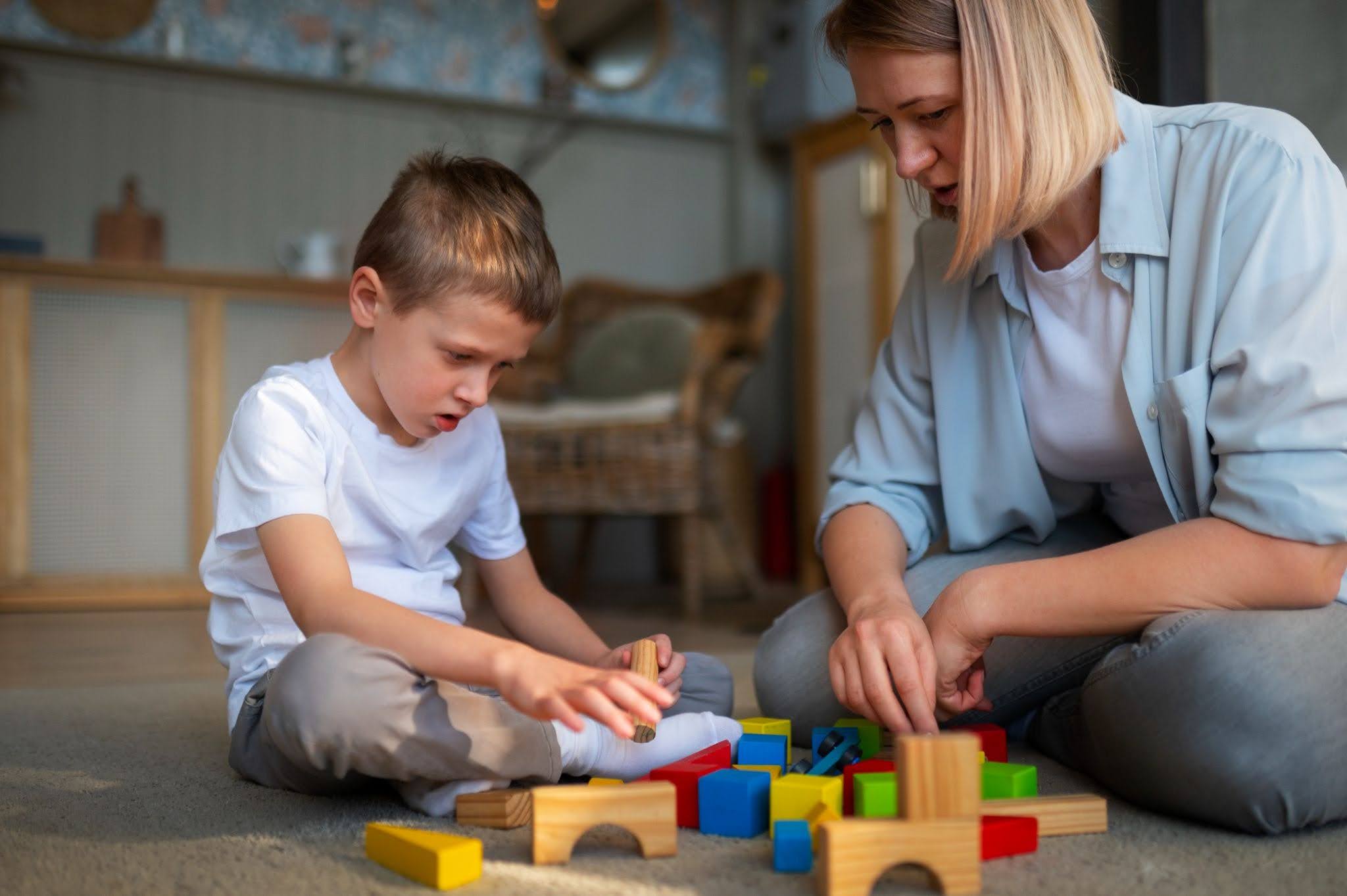 A kid and his mother playing with wooden blocks.