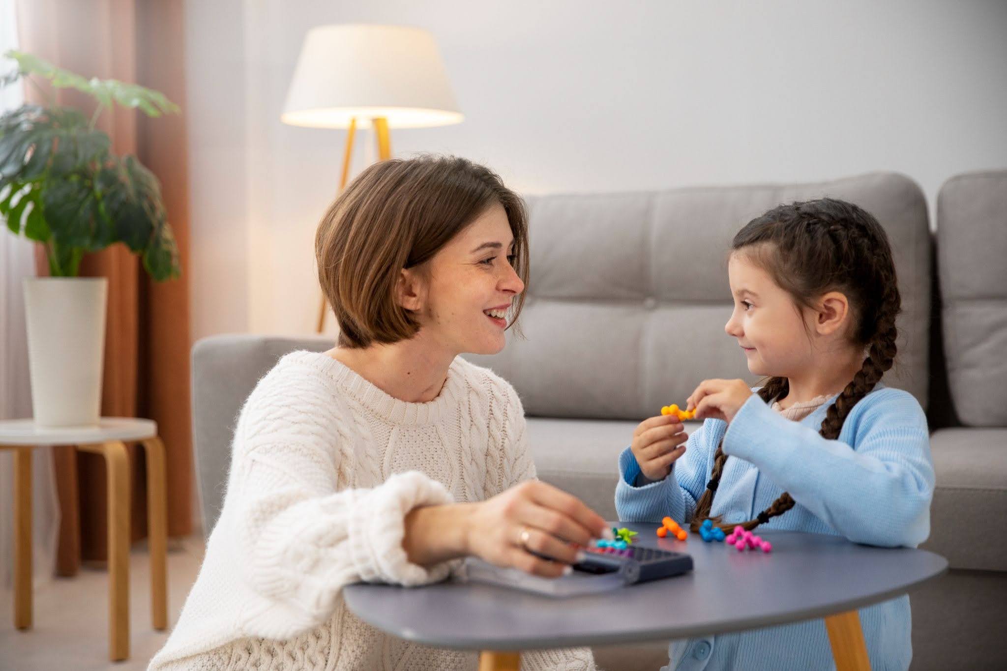 A girl playing with toys while her mother is looking over her.