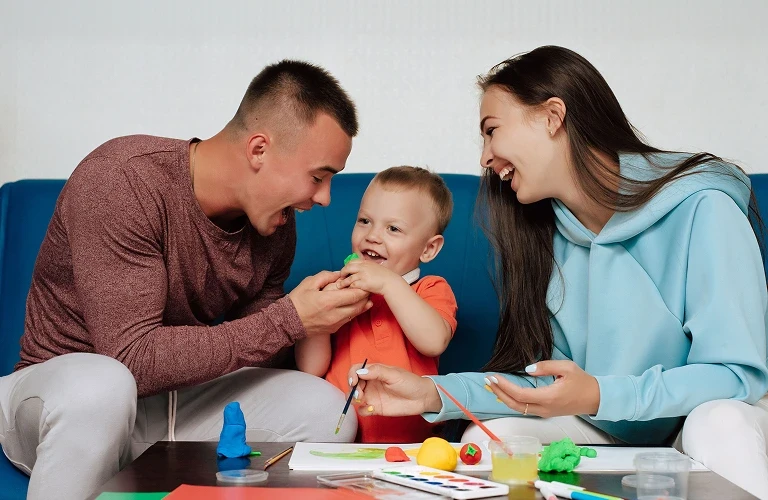 Two parents and their young child playing on the floor with a therapist.