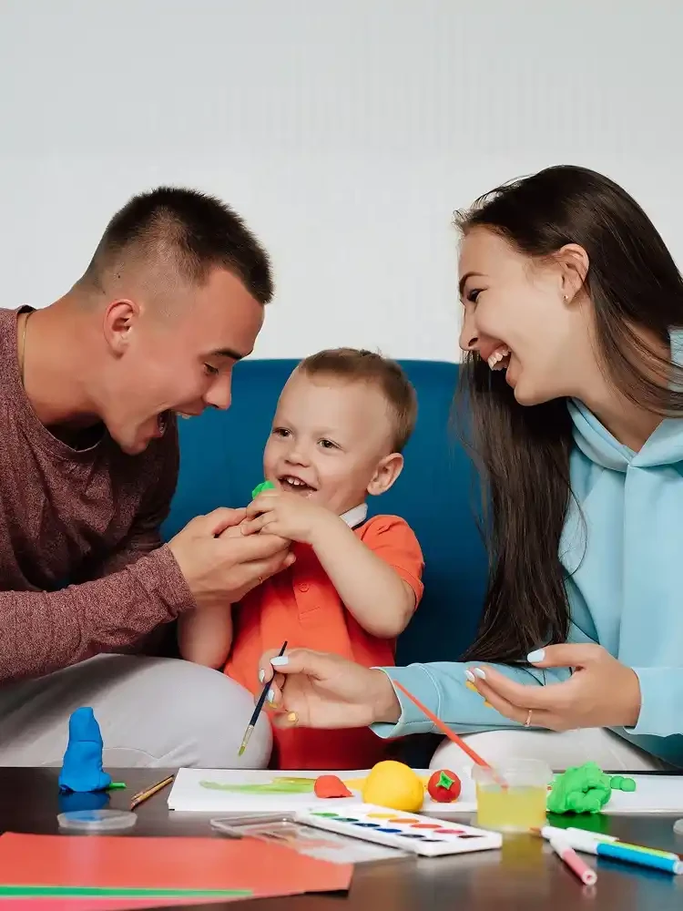 Two parents and their young child playing on the floor with a therapist.